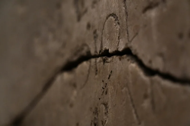 Primer plano de una grieta oscura y profunda en una superficie de cerámica o piedra clara.