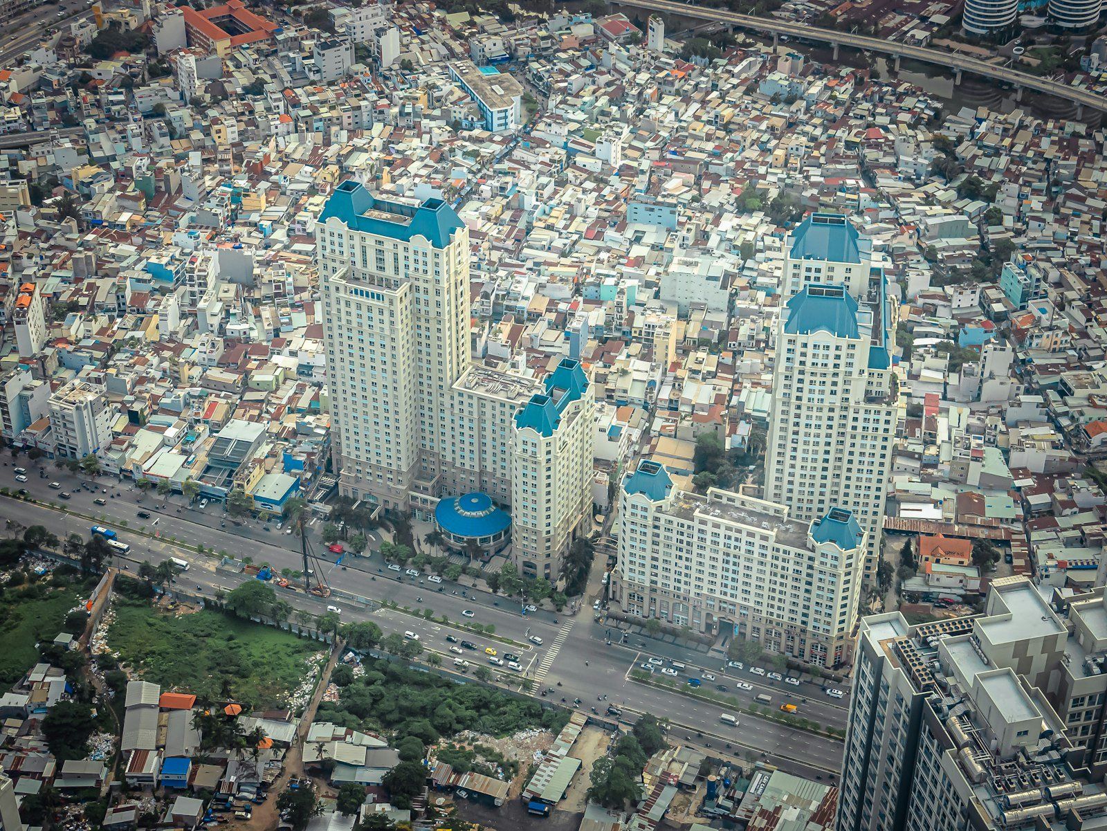 Vista aérea de Ho Chi Minh con rascacielos azules y blancos sobre barrios densos y calles bulliciosas