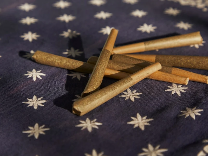 Varios porros enrollados de tono marrón sobre tela azul marino con estrellas blancas