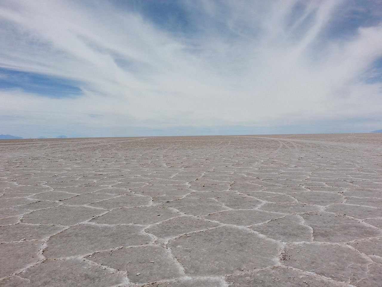 Vasta extensión del Salar de Uyuni con patrones hexagonales de sal y cielo nublado.
