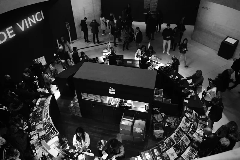 Vista aérea en blanco y negro de una tienda con personas, estanterías curvas y un letrero luminoso.