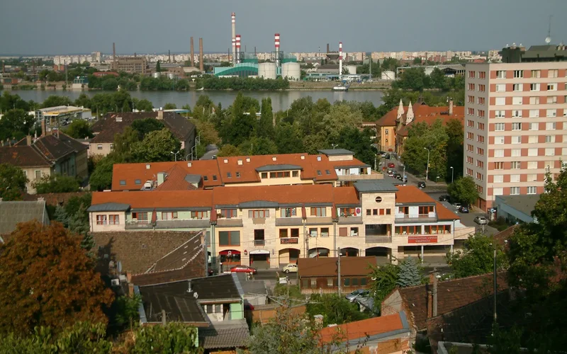 Vista panorámica de Isla Csepel con edificios residenciales de techos rojos, chimeneas industriales altas y el río al fondo
