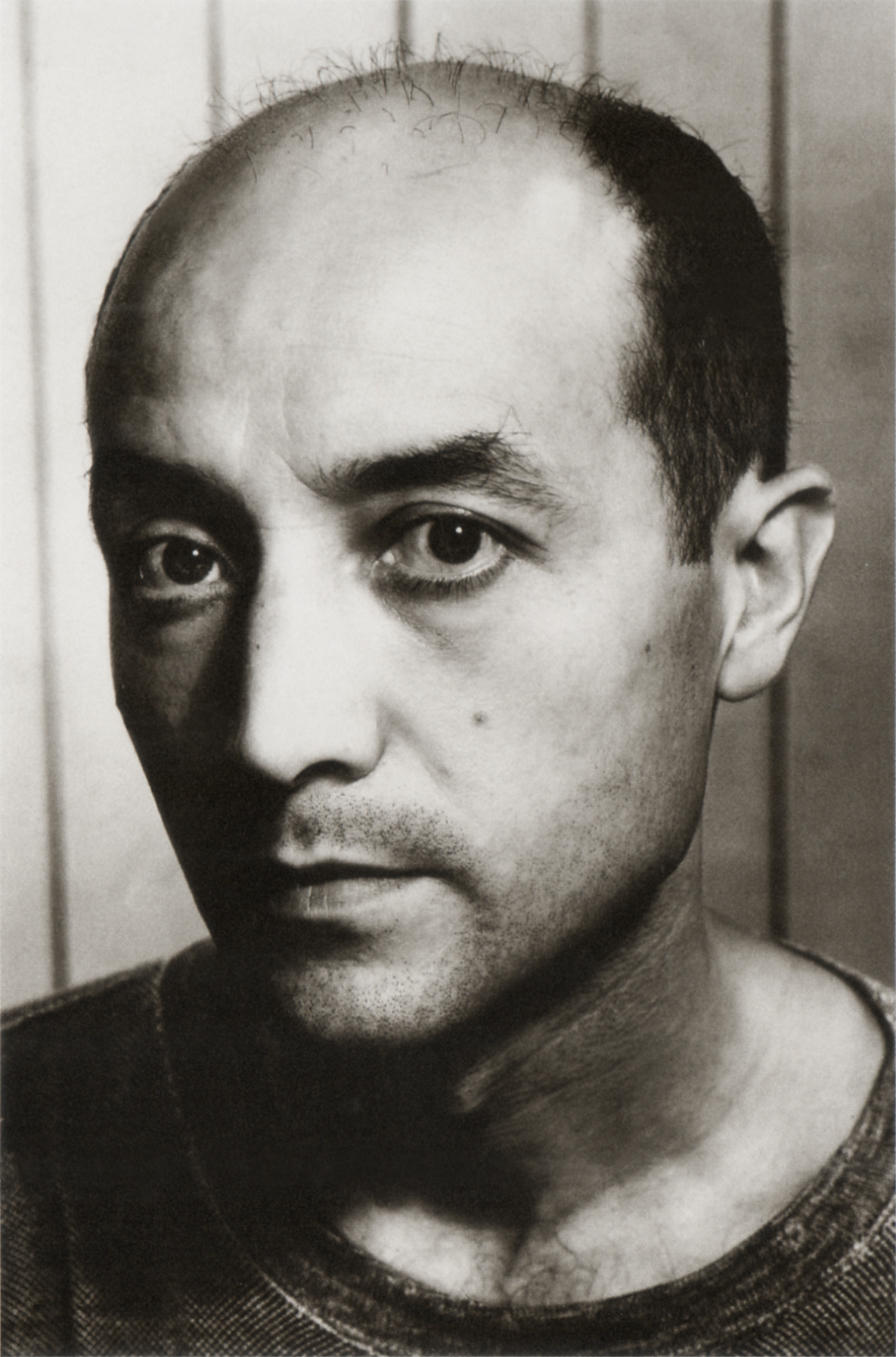 Retrato en blanco y negro de un hombre con cabello oscuro escaso y ojos grandes.