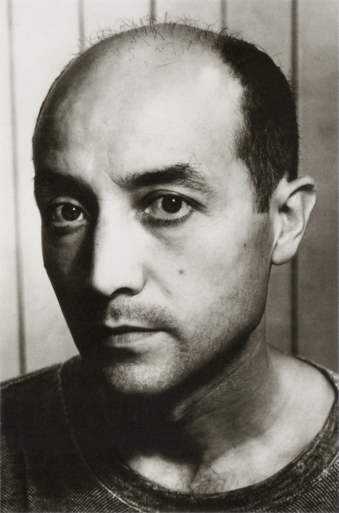 Retrato en blanco y negro de un hombre con cabello oscuro escaso y ojos grandes.