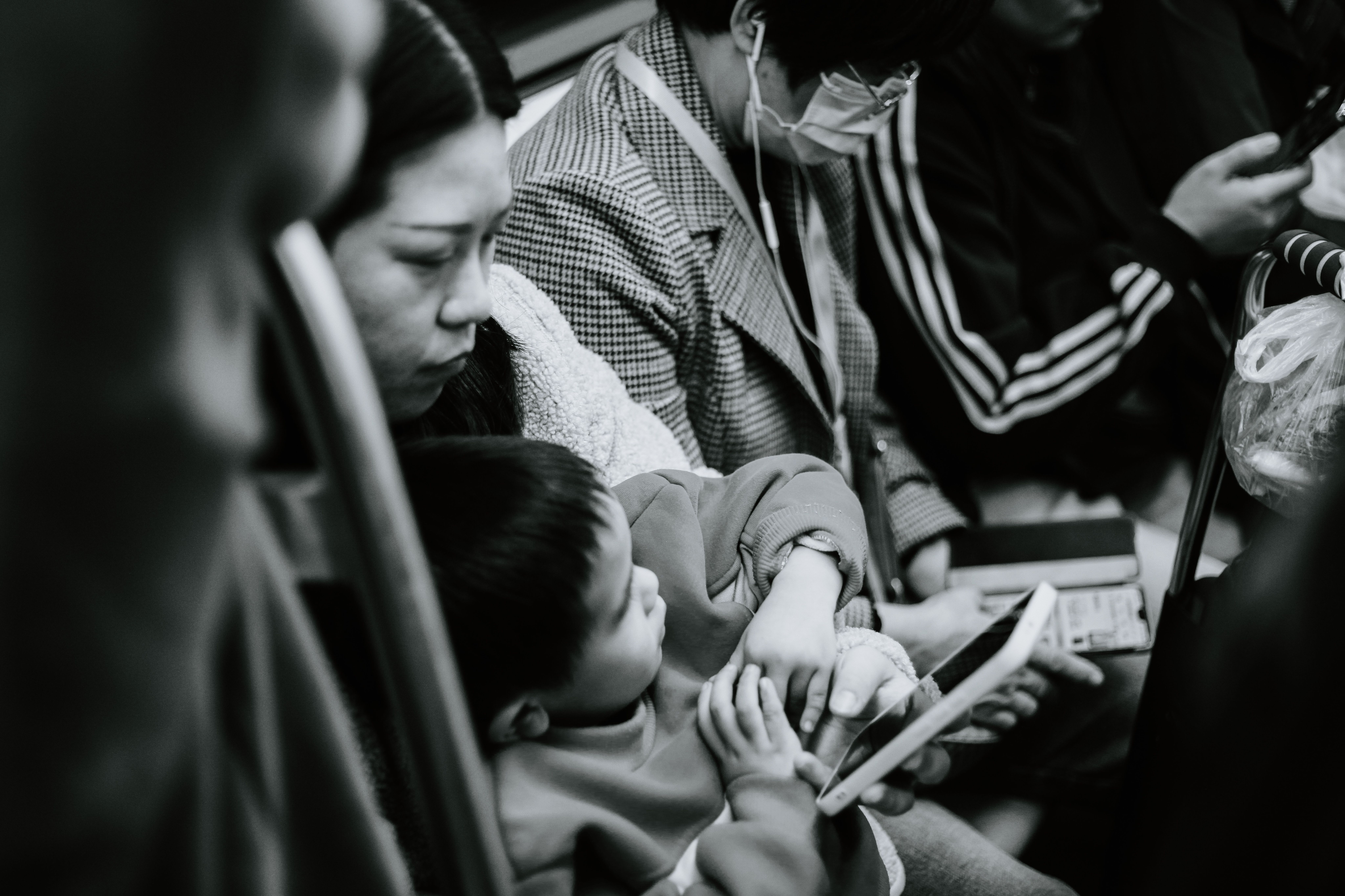 Mujer y niño sentados en un transporte público, el niño mira una pantalla de móvil.
