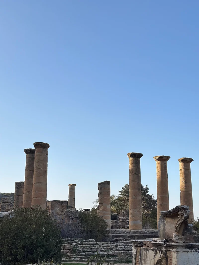 Columnas de piedra antiguas y ruinas de una ciudad bajo un cielo azul claro.