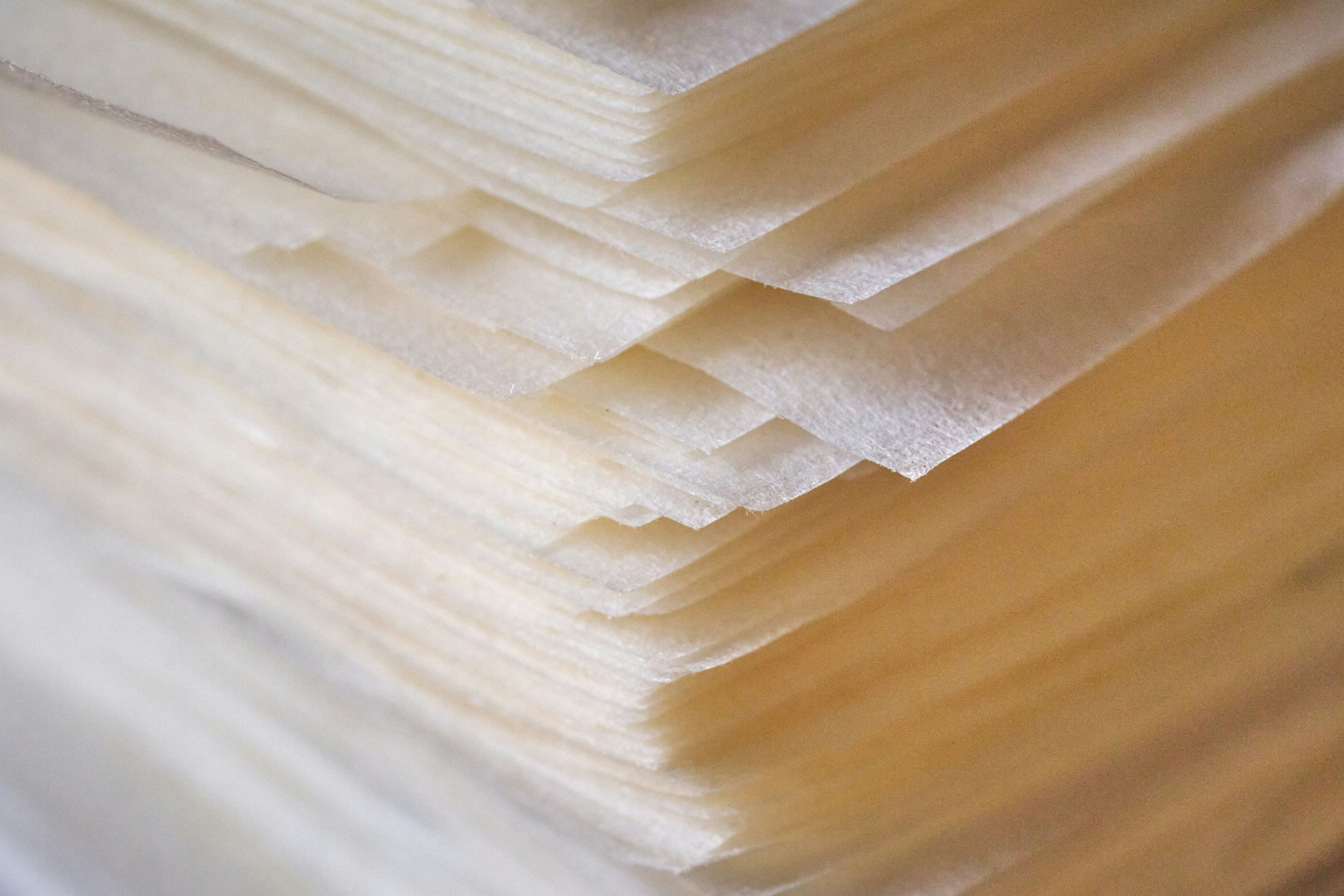Primer plano de una pila de hojas de papel translúcido de color blanco cremoso.