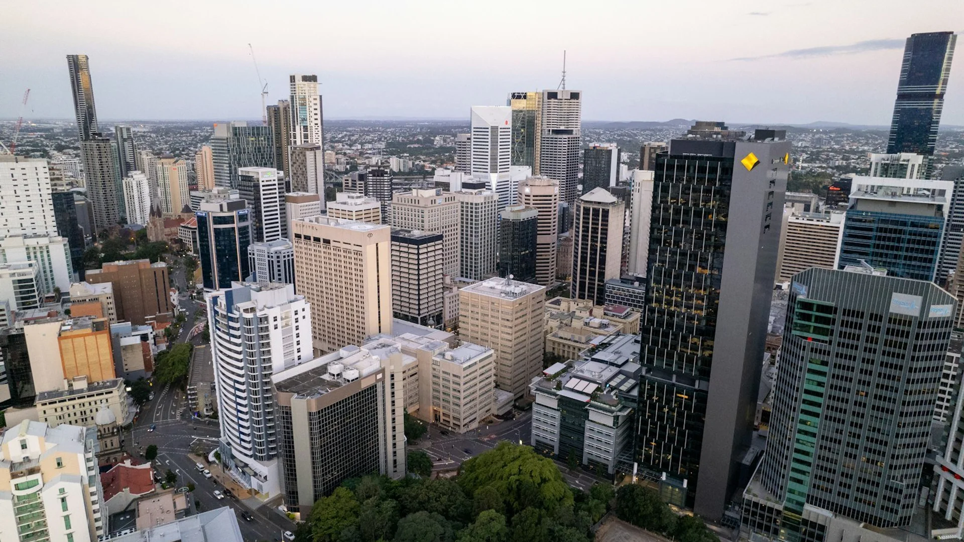 Vista panorámica de Brisbane al atardecer con el río Brisbane serpenteando entre rascacielos modernos y el Story Bridge iluminado