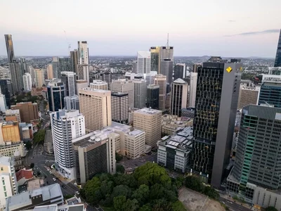 Vista aérea del skyline de Brisbane al atardecer, con rascacielos modernos, vegetación verde y cielo rosado