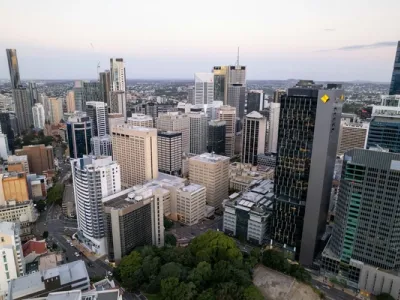 Vista aérea del skyline de Brisbane al atardecer, con rascacielos modernos, vegetación verde y cielo rosado