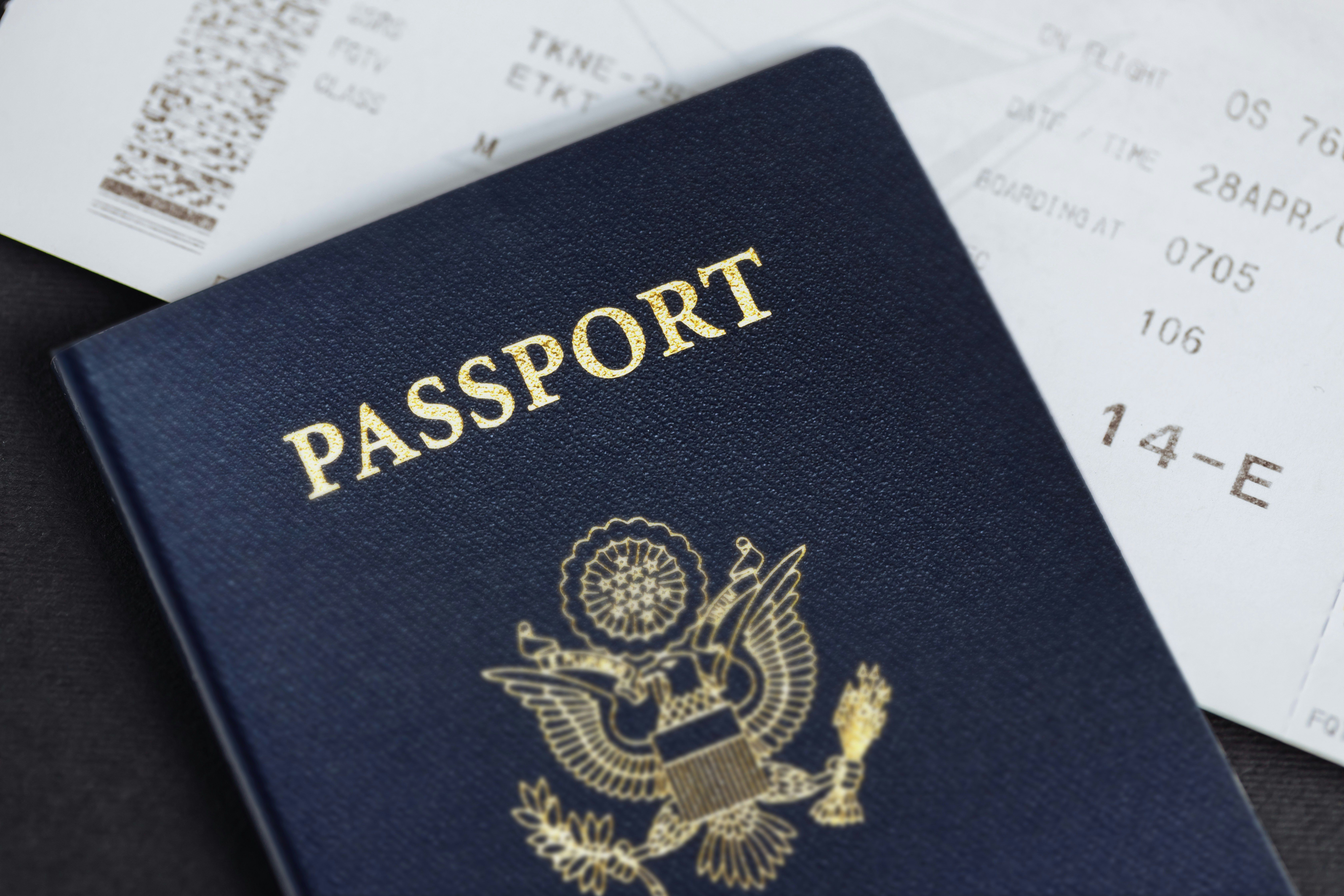 Primer plano de un pasaporte azul con la palabra "PASSPORT" y un billete de avión.