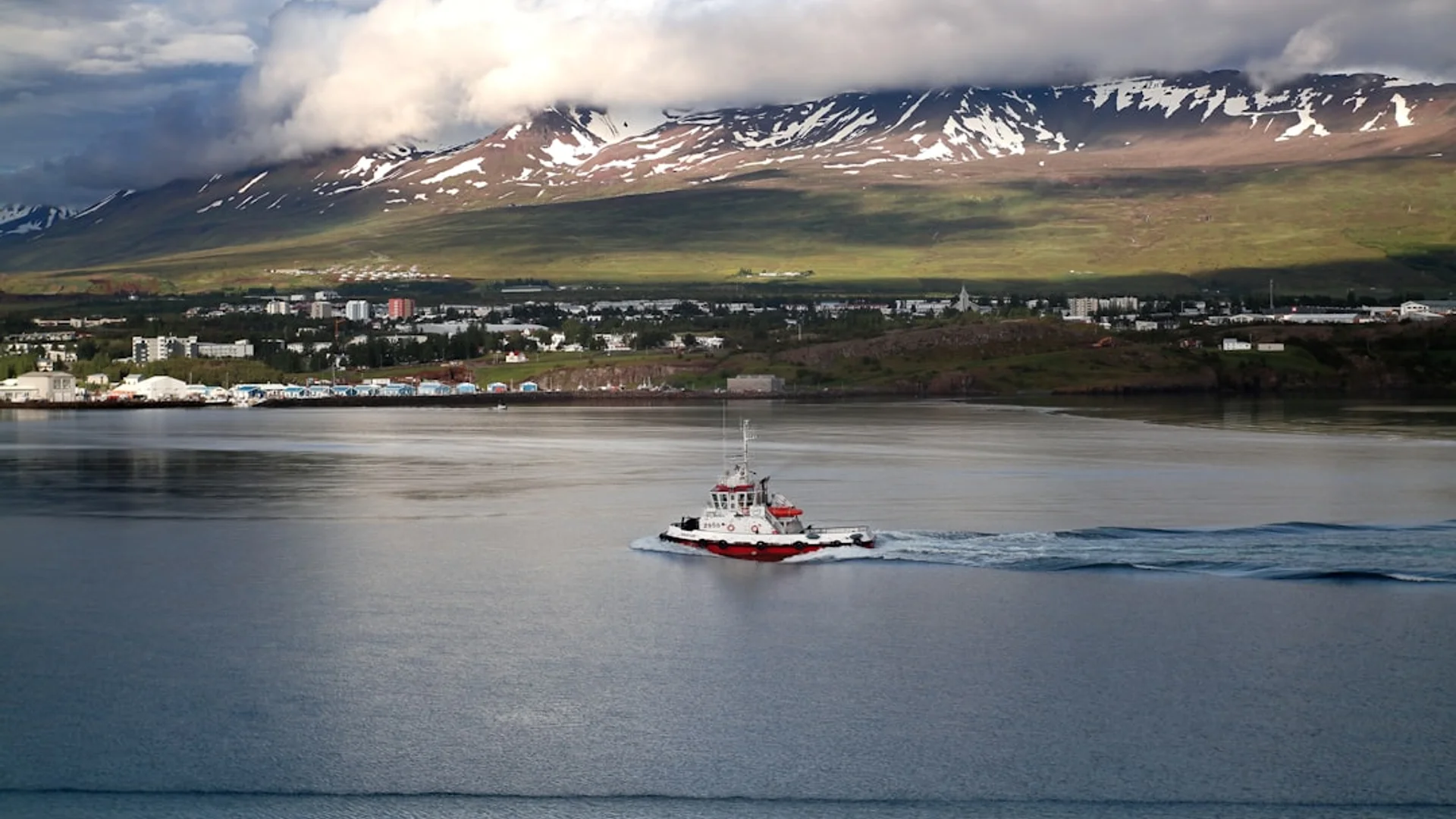 Vista panorámica de Akureyri bajo la luz del atardecer, con sus casas coloridas descendiendo hacia el fiordo Eyjafjörður y montañas nevadas al fondo