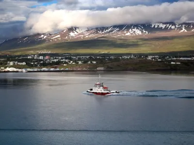 Vista panorámica de Akureyri bajo la luz del atardecer, con sus casas coloridas descendiendo hacia el fiordo Eyjafjörður y montañas nevadas al fondo