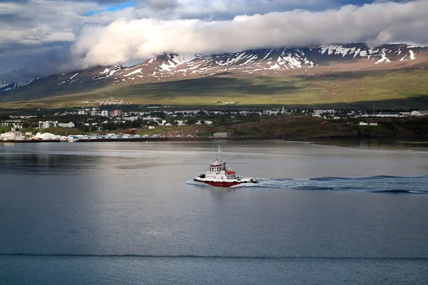 Vista panorámica de Akureyri bajo la luz del atardecer, con sus casas coloridas descendiendo hacia el fiordo Eyjafjörður y montañas nevadas al fondo