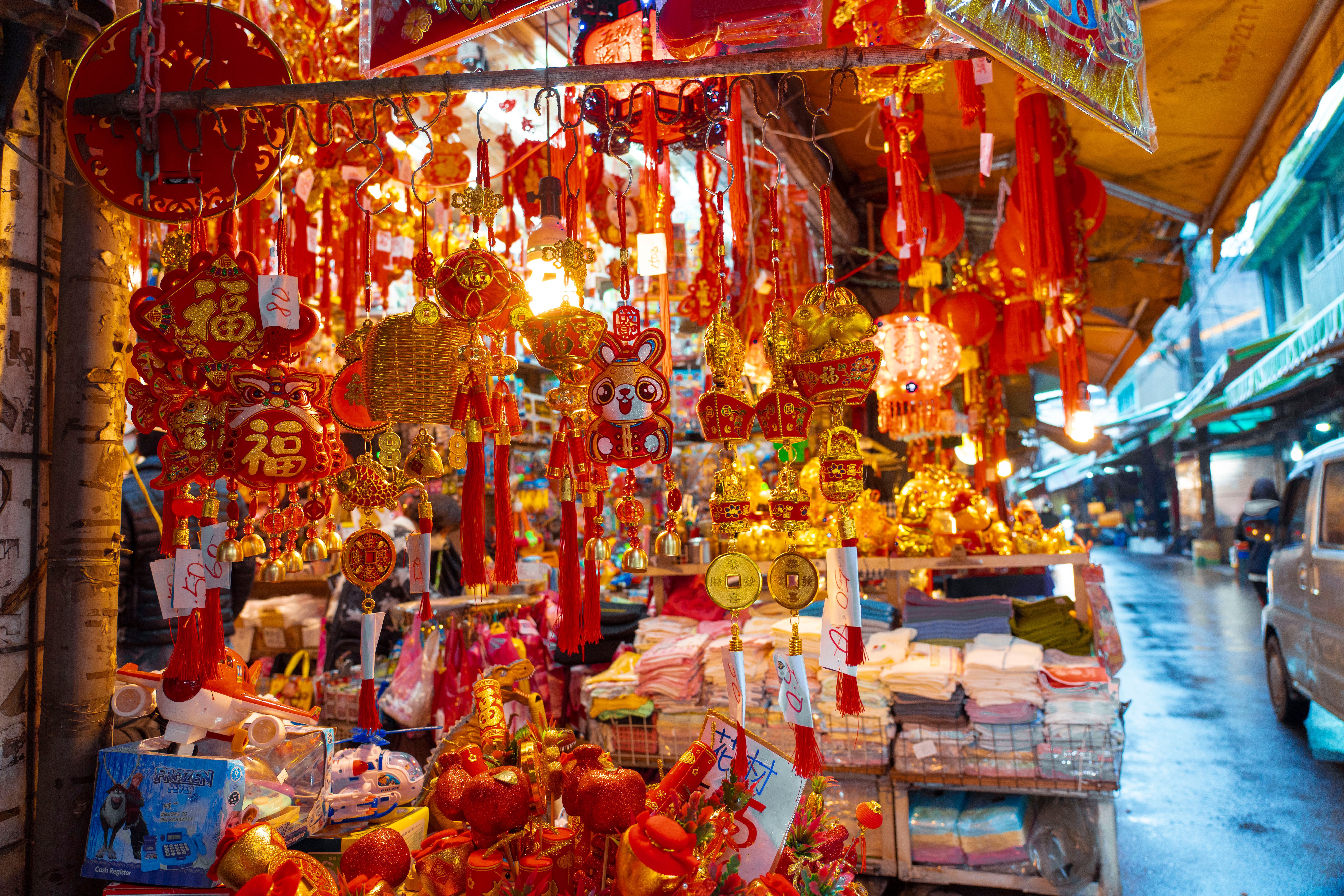 Un puesto de mercado chino lleno de adornos rojos y dorados, linternas y amuletos.