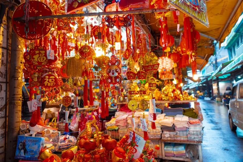 Un puesto de mercado chino lleno de adornos rojos y dorados, linternas y amuletos.