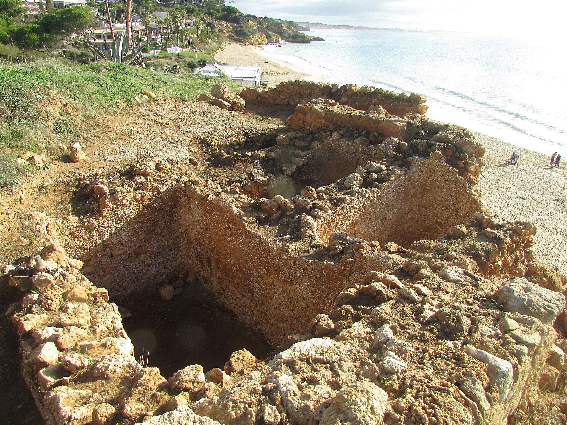 Restos de una antigua planta romana de procesamiento de pescado junto a una playa arenosa.
