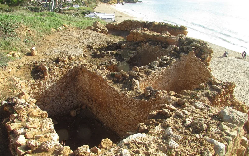 Restos de una antigua planta romana de procesamiento de pescado junto a una playa arenosa.