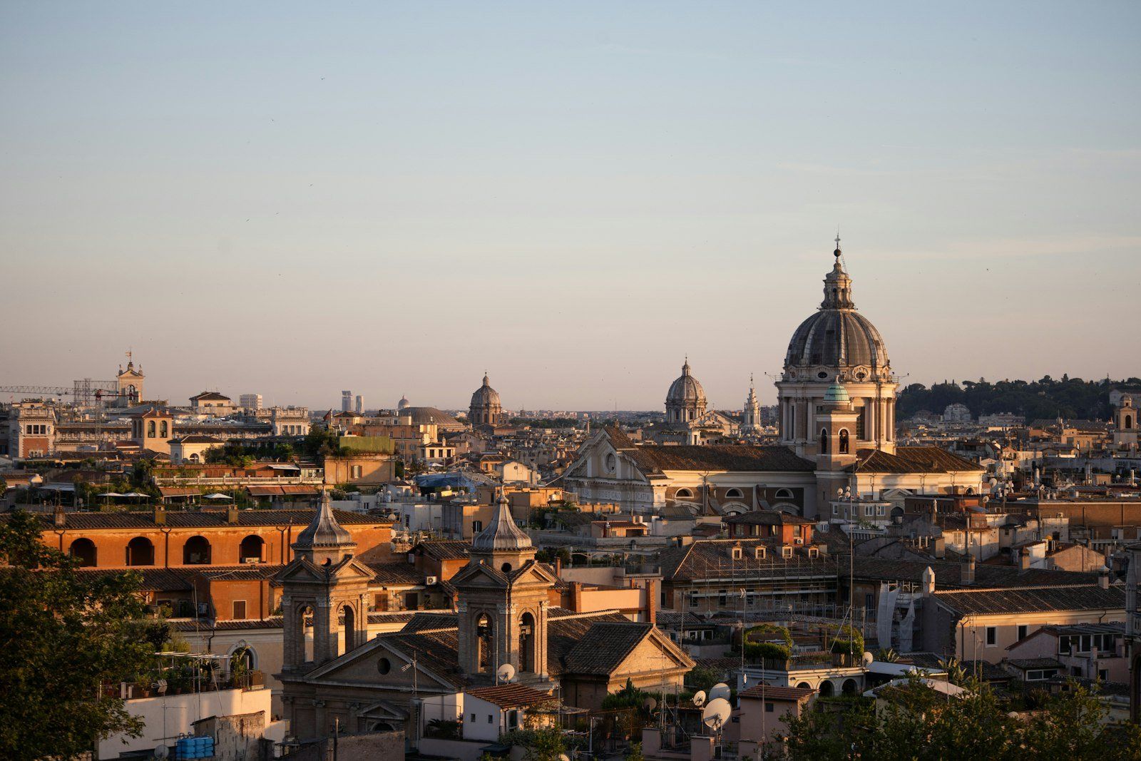 Vista panorámica de Roma al atardecer, con cúpulas de iglesias y edificios antiguos bajo un cielo azul rosado