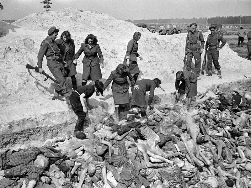 Guardianas de las SS del campo de concentración de Bergen-Belsen descargan cadáveres de prisioneros para enterrarlos en una fosa común. Fueron reclutadas para este trabajo por los Aliados que liberaron el campo. Un convoy de soldados británicos rodea la zanja. A las antiguas guardianas se las castiga prohibiéndoles usar guantes, lo que las expone al riesgo de contraer tifus. En la imagen