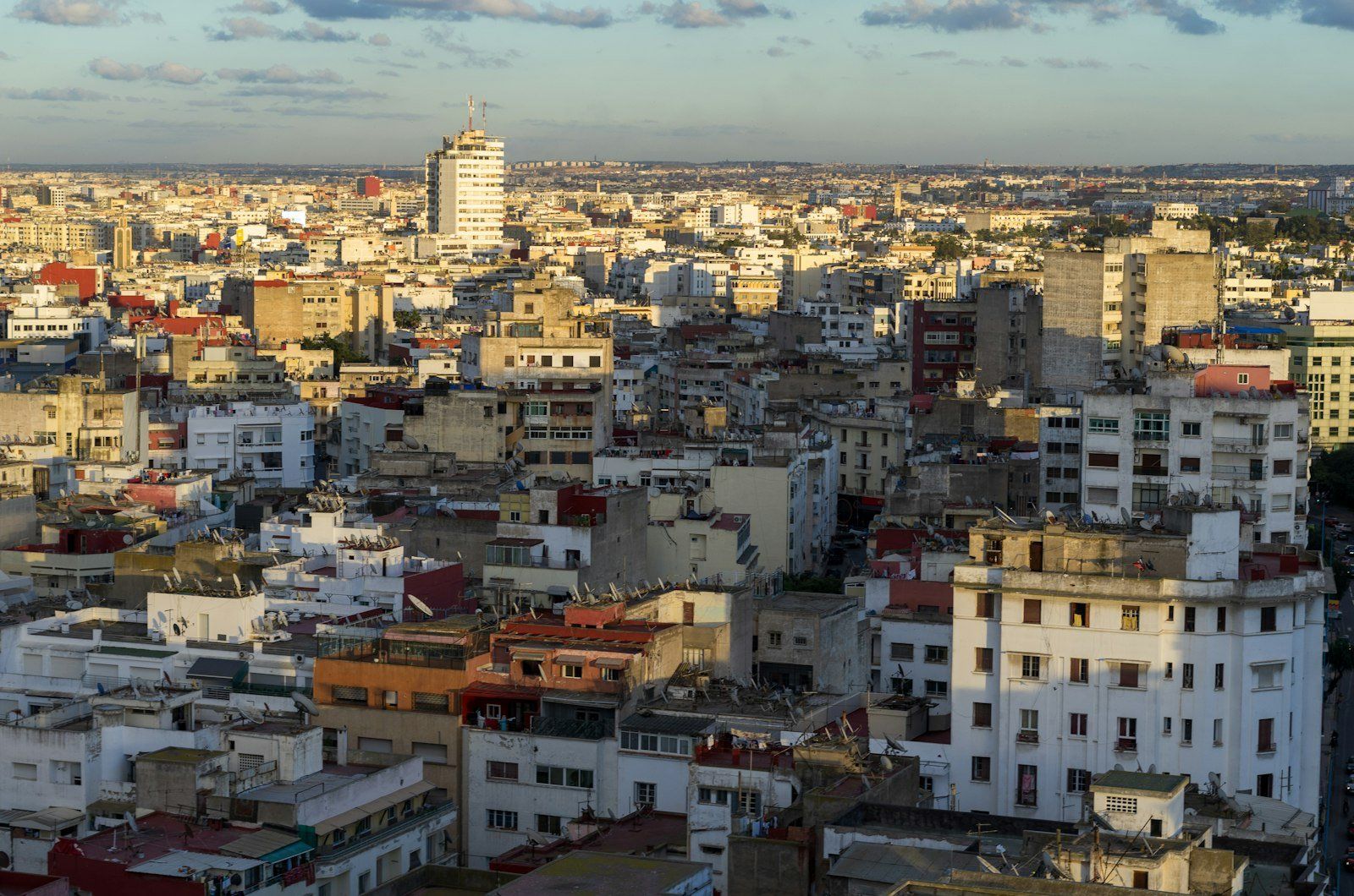 Vista panorámica de Casablanca al atardecer, con edificios densos de varios pisos en tonos beige y rojos bajo un cielo nublado