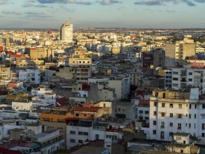 Vista panorámica de Casablanca al atardecer, con edificios densos de varios pisos en tonos beige y rojos bajo un cielo nublado