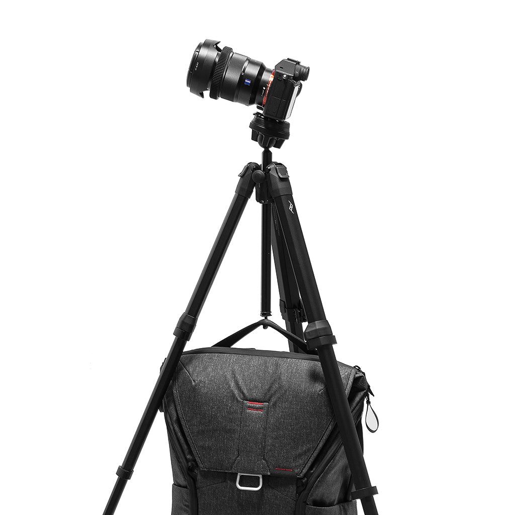 A camera bag hangs from the Peak Design Travel Tripod center column hook