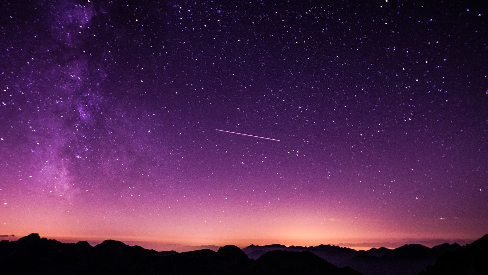Milky Way galaxy over dark mountain peaks under a starry night sky