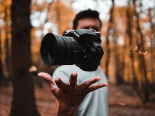 Photographer using a speedlight outdoors during a portrait session in bright sunlight