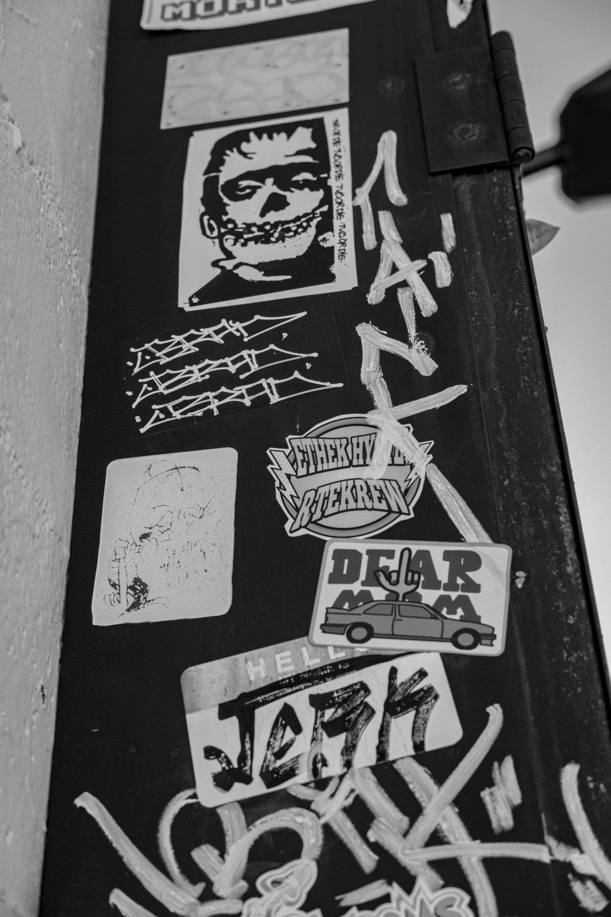 Looking up the side of a dark box tagged with stickers, a skull face at the top.