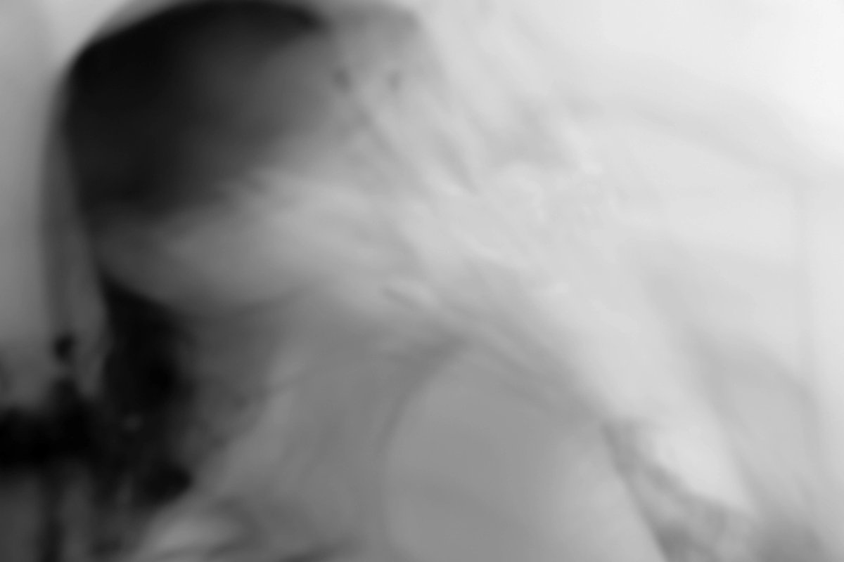 A blurred figure turns away under falling water, almost dissolved into white.