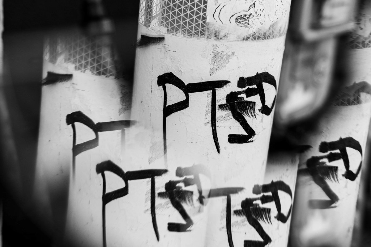 Several white poles, each painted 'PTSD', overlapping in a blurred, layered image.