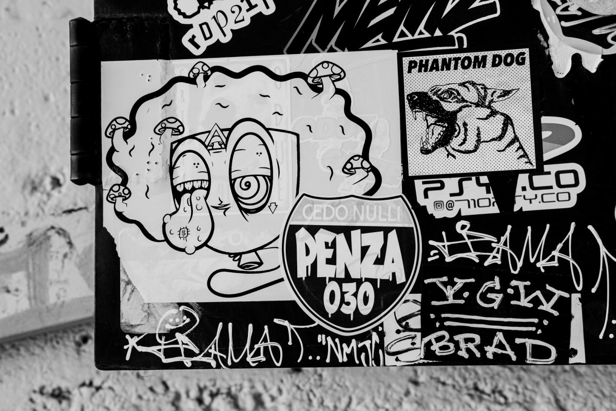 A cluster of stickers: a cartoon monster with mushrooms, a snarling dog, and a road-sign shield reading 'Penza 030'.