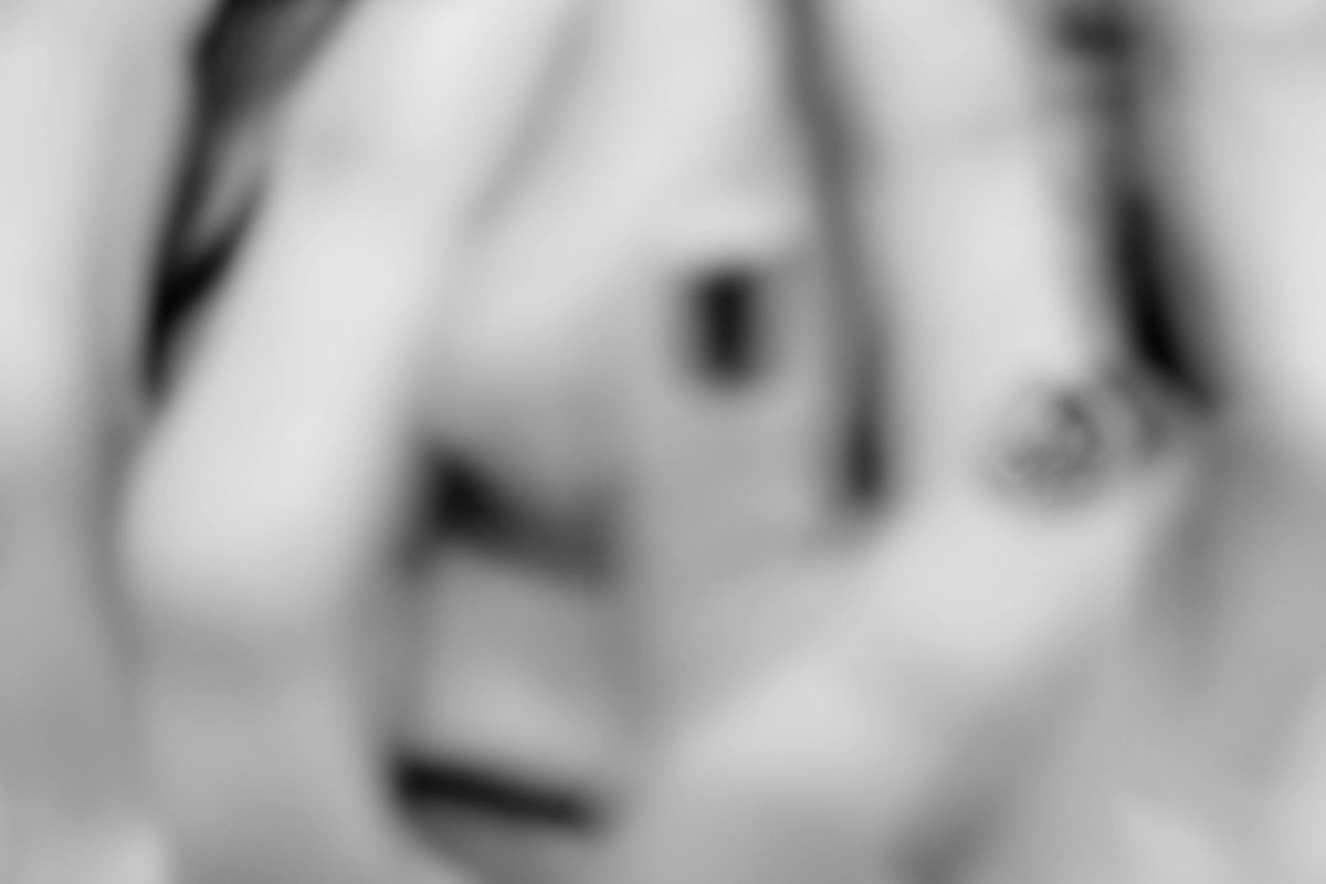 A face pressed close behind spread fingers, one dark eye visible, everything softly out of focus.