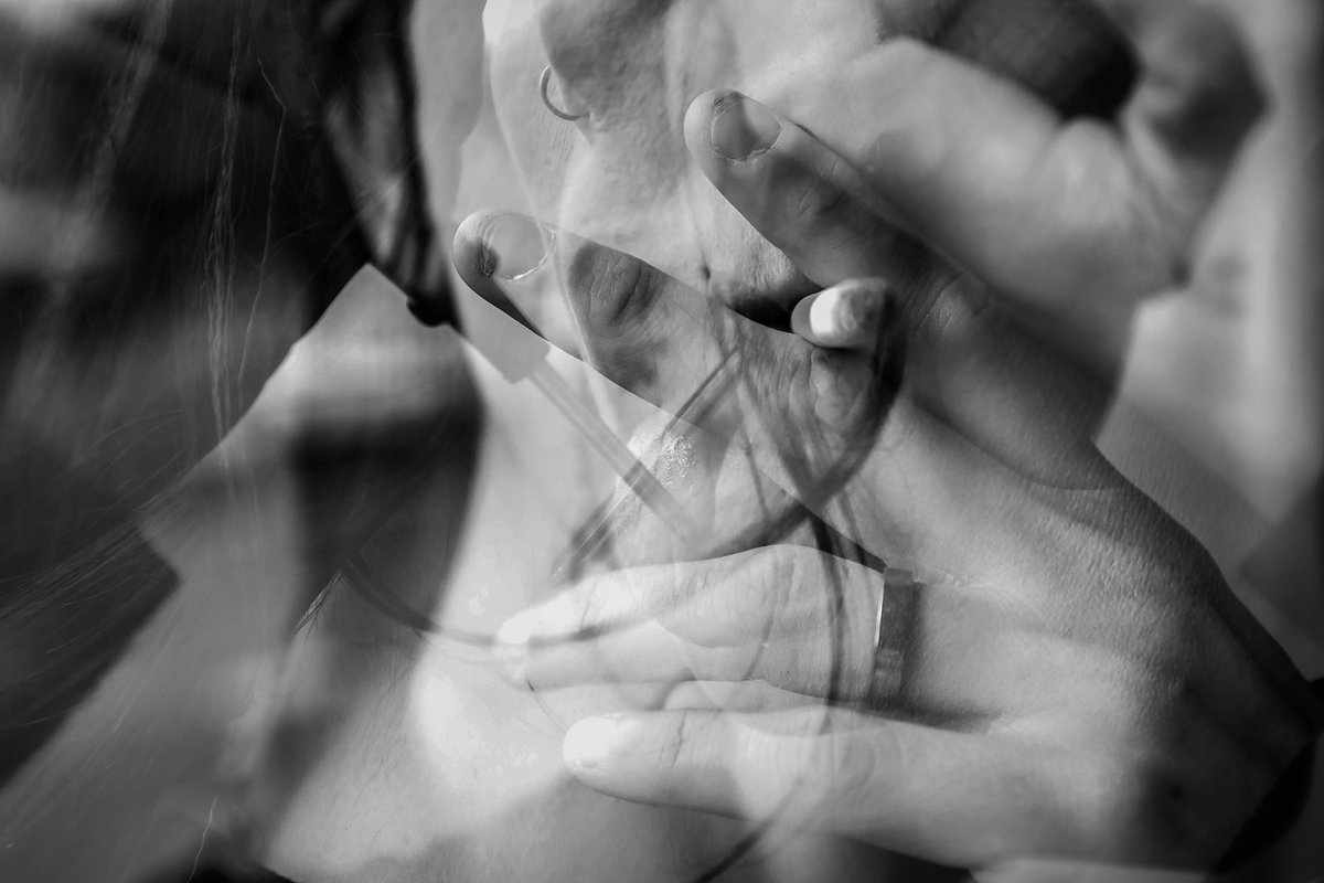 Overlapping hands and a face in a smoky multiple exposure, a ring on one finger.