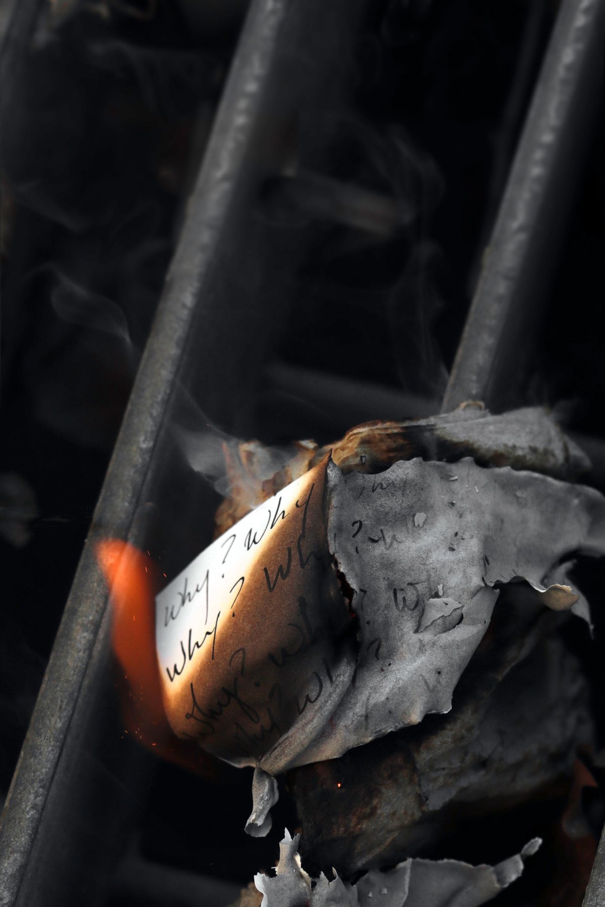 A handwritten page curls and burns on a metal grate, 'Why?' visible on its last unburned edge.