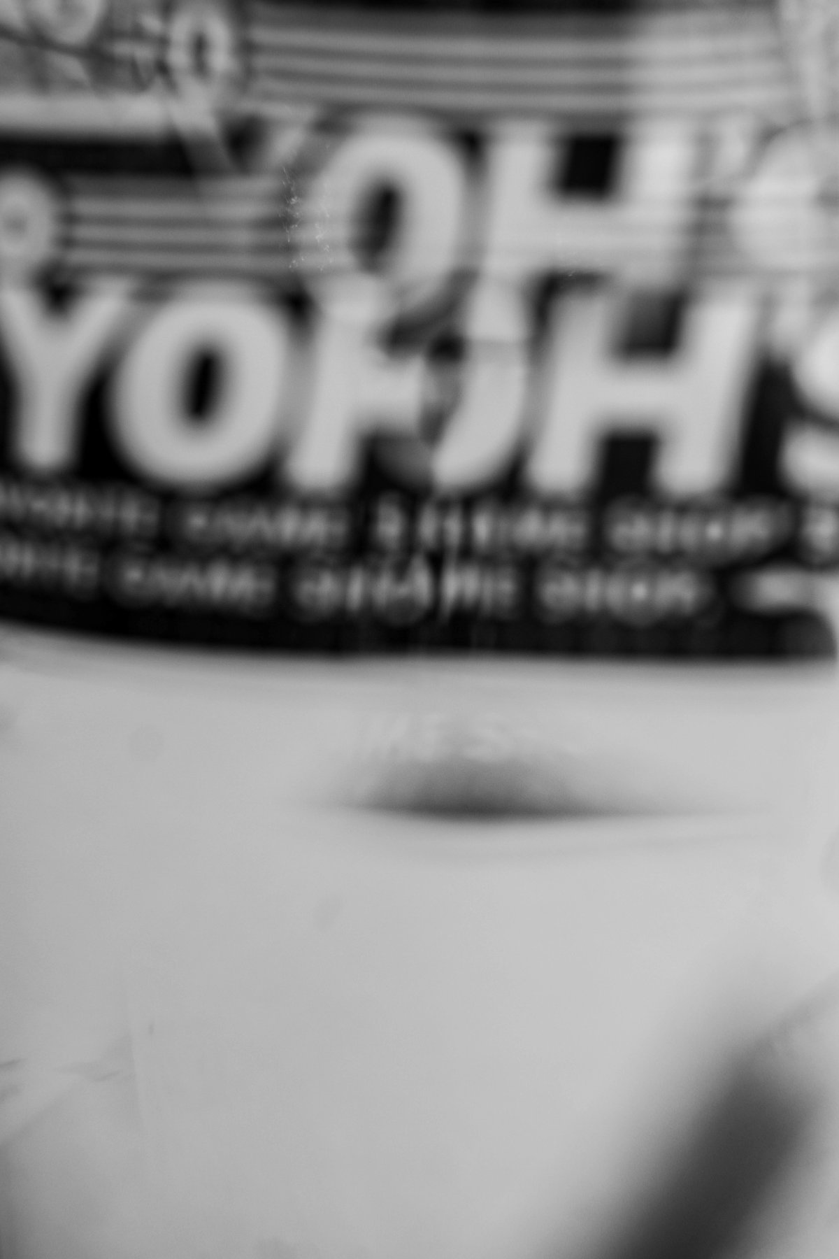 A blurred sticker with large letters at the top, and a soft dark shape below.