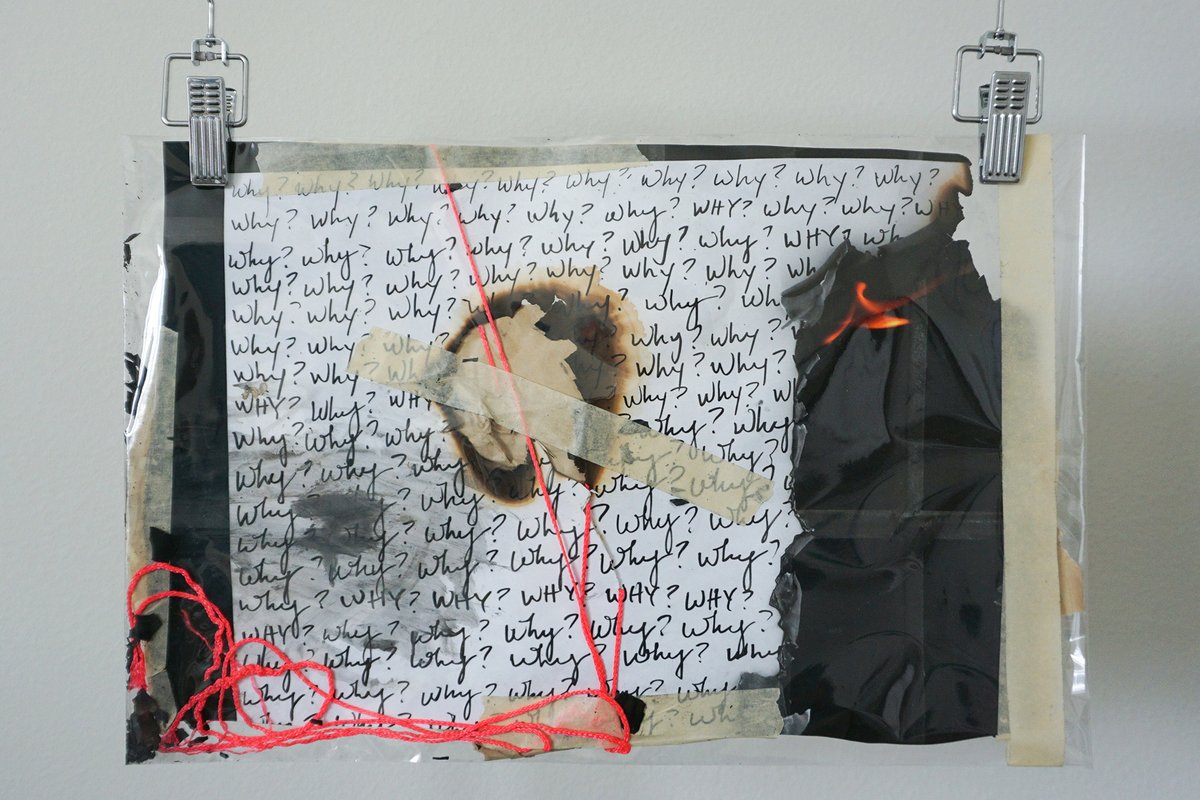 A collage of 'Why?' pages, burn holes, tape and tangled red string, clipped to a wall.