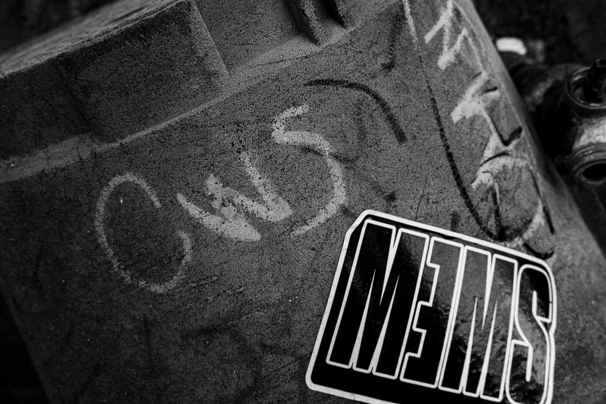Close-up of the dented gutter, chalk scrawl and a bold black sticker.