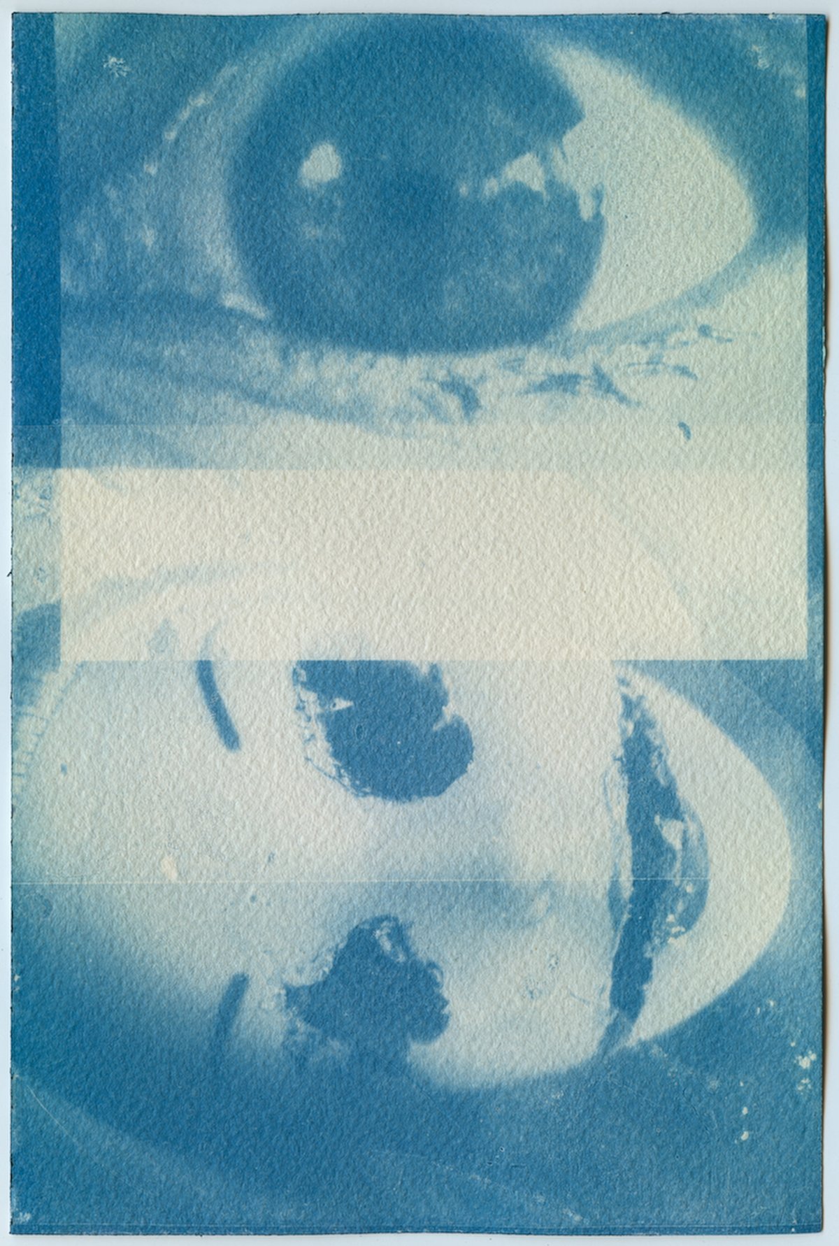 A cyanotype in two layers: a huge eye at the top, and a doll's face lying sideways below.