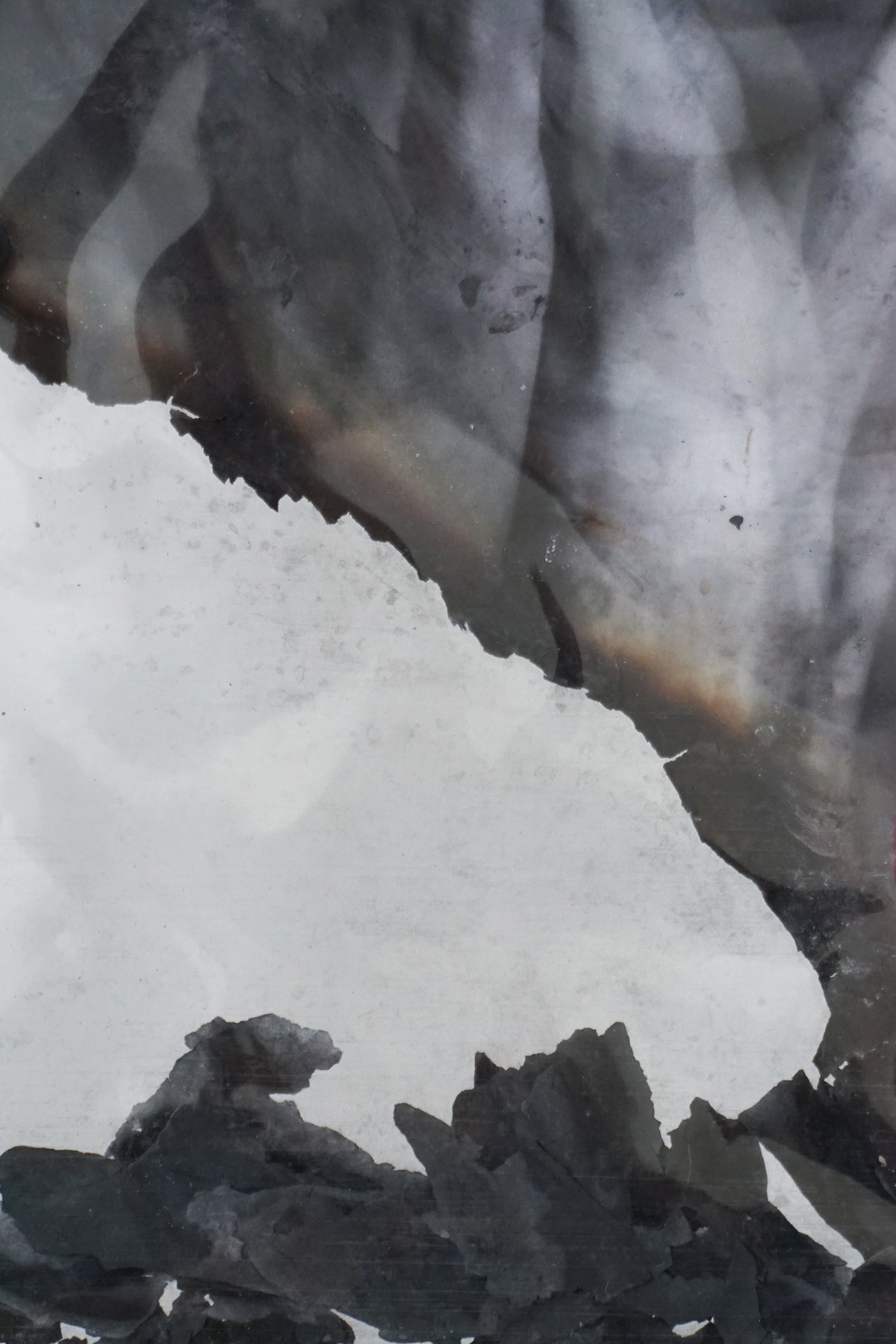 Detail of a burned print: charred black edges against pale paper.
