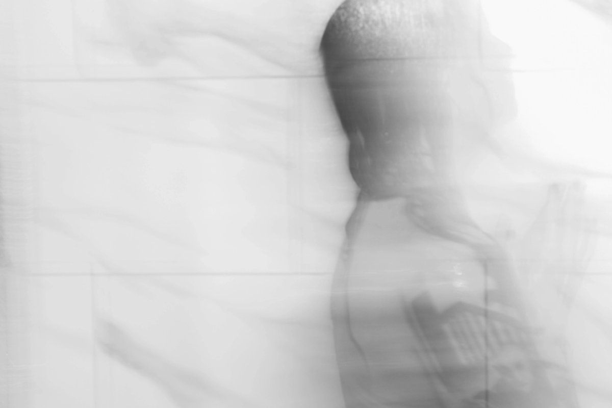 A figure blurred into a white shower, more ghost than body.
