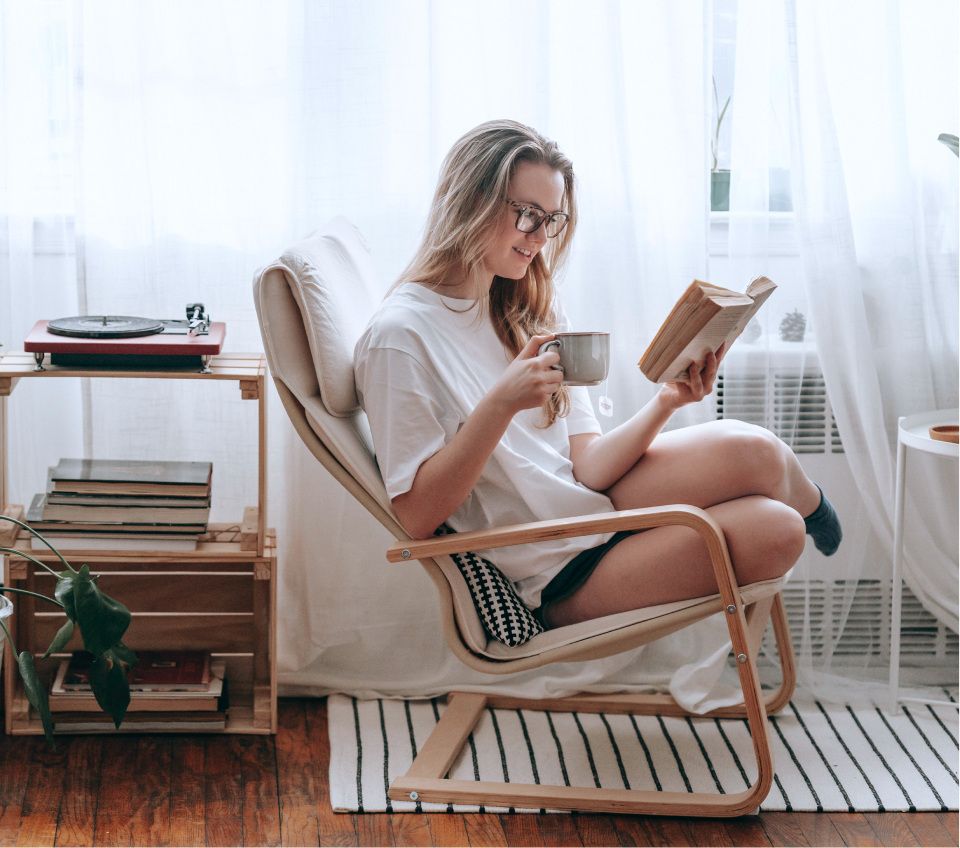 A person sitting in a chair enjoying a good book and cup of tea