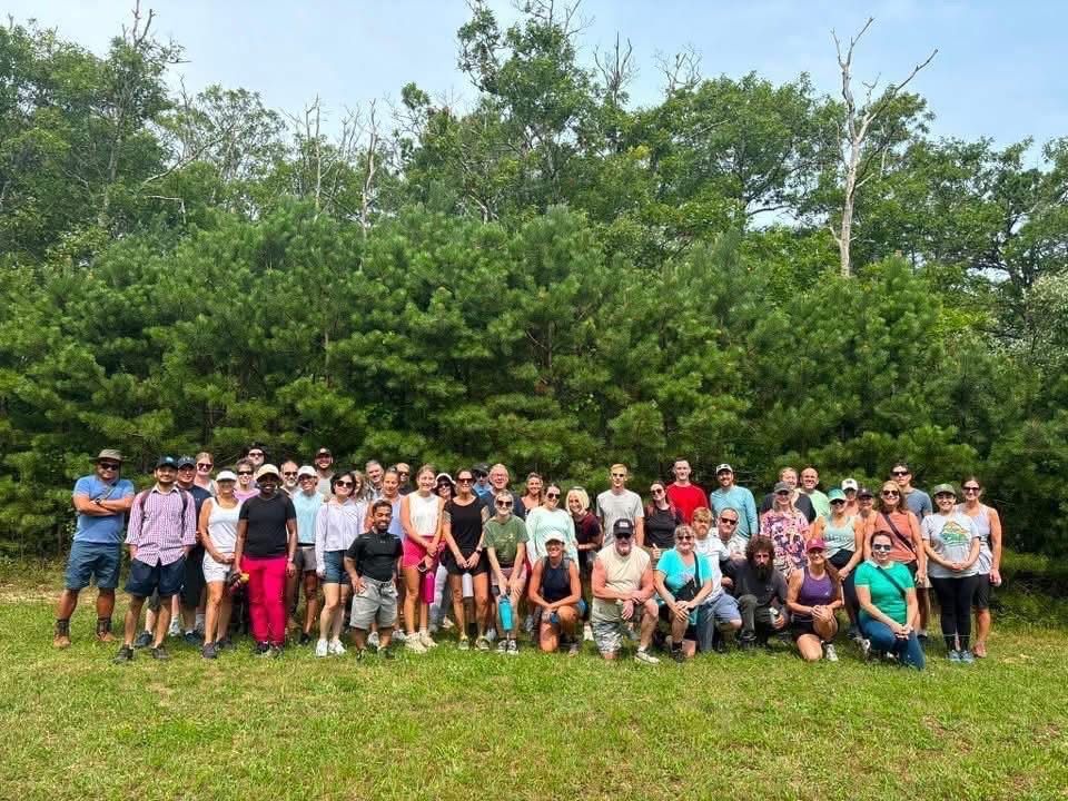 Large group of hikers standing in front of trees.