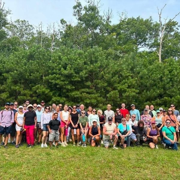 Large group of hikers standing in front of trees.