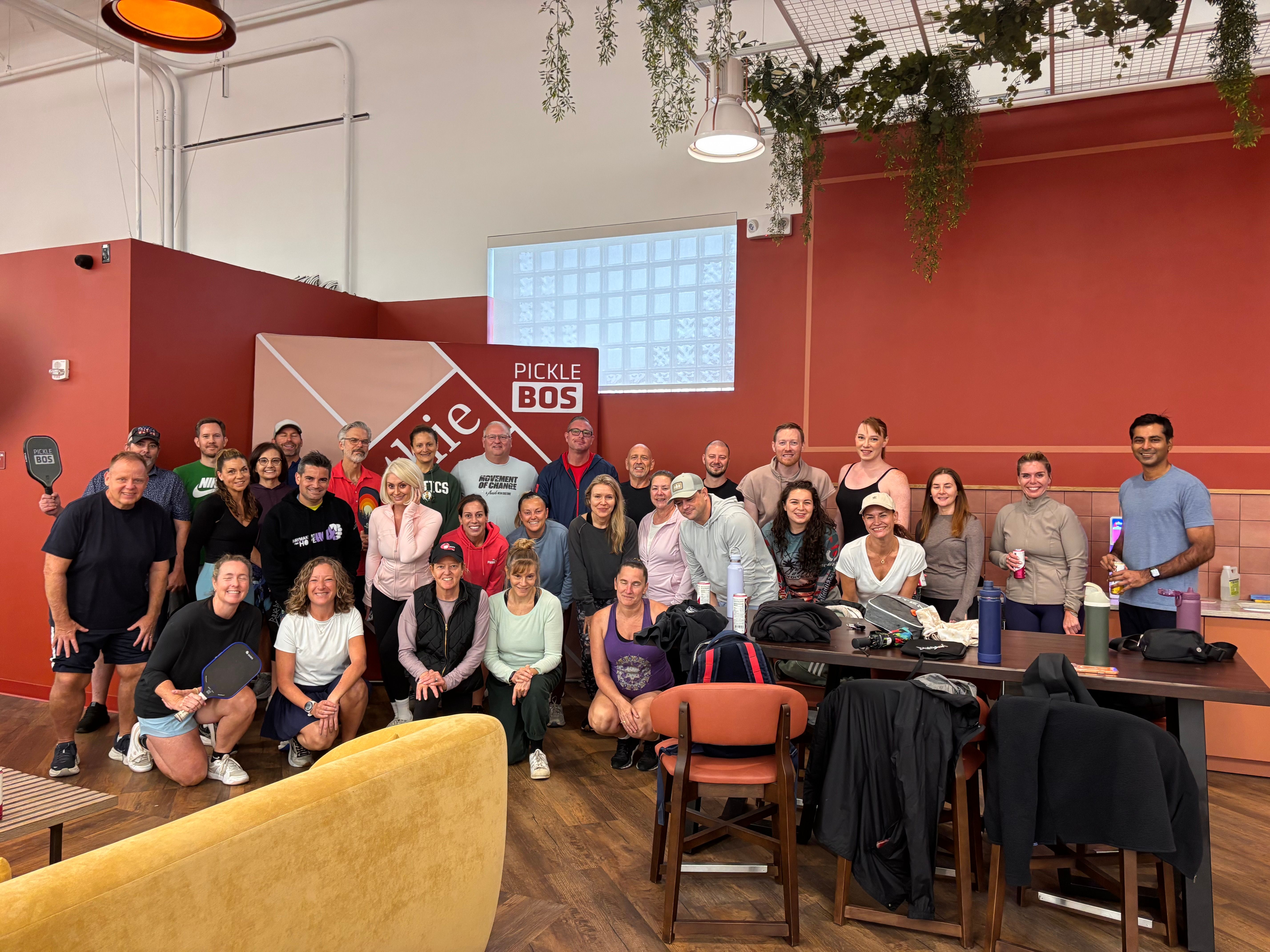 Large group posing in front of the pickleball signage.