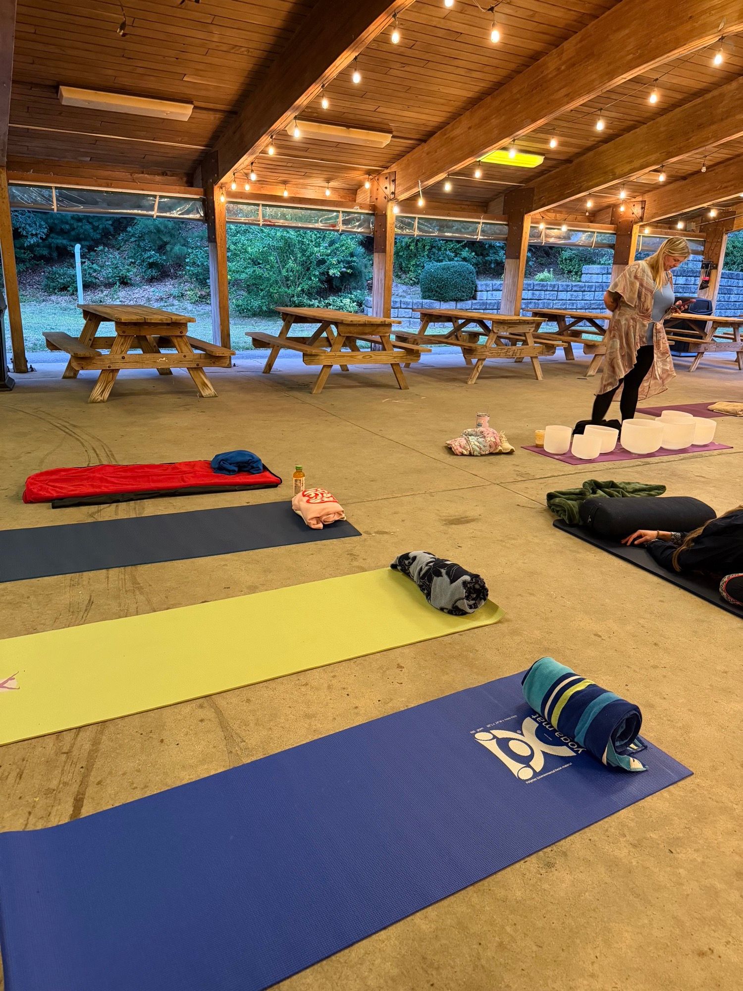 Mats and blankets laid out in rows across the pavilion floor, with people gathering at the far end.