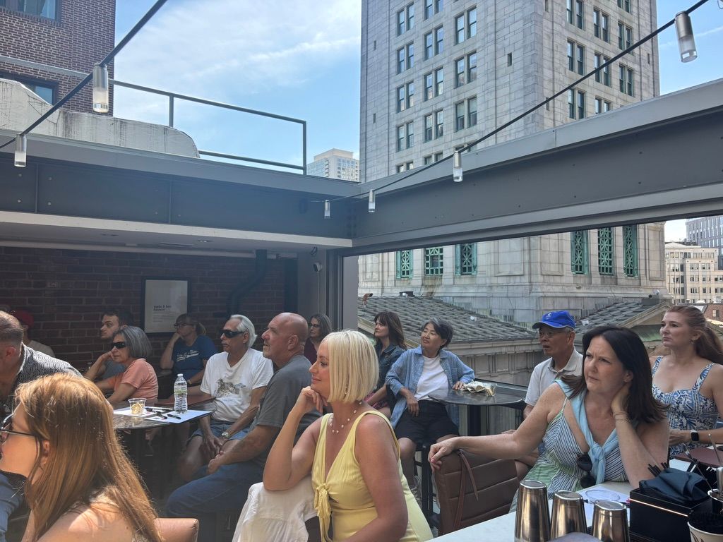 Group of people seated with an open air roof above. 
