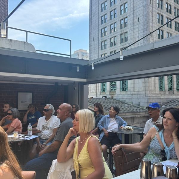 Group of people seated with an open air roof above.