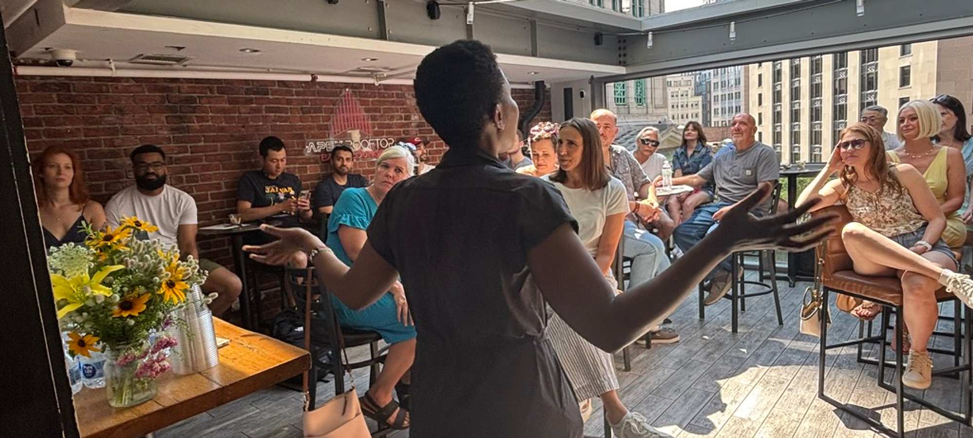 A woman addressing a crowd of seated guests at a coffee tasting.
